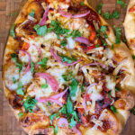 tandoori chicken naan pizza served on a pizza board