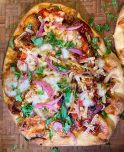 tandoori chicken naan pizza served on a pizza board